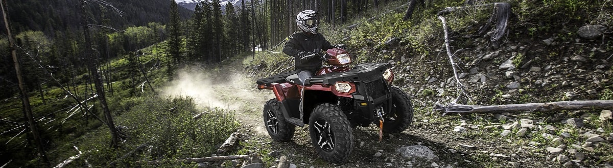 Man riding an ATV on a trail in the woods